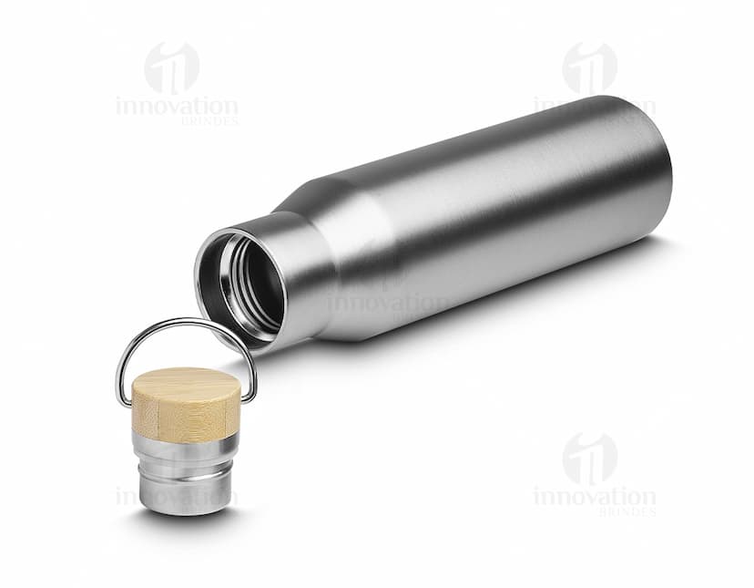 Garrafa térmica de 600ml em metal prateado, com design antigo e acabamento brilhante. O equipamento é feito de aço inoxidável e possui plug elétrico, indicando sua função de manter bebidas quentes ou frias. A embalagem possui rótulo em papel cinza com letra preta, e a tampa é de plástico preto. A garrafa térmica é mostrada em close-up, refletindo luz e sombras em sua superfície metálica.