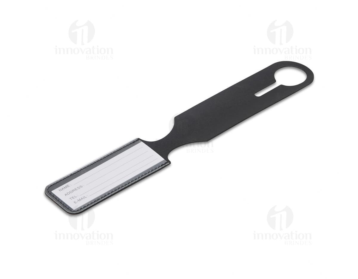 Identificador de Bagagem em metal prateado, com alça preta e plástico transparente para inserir informações. Item útil para identificar malas durante viagens.
