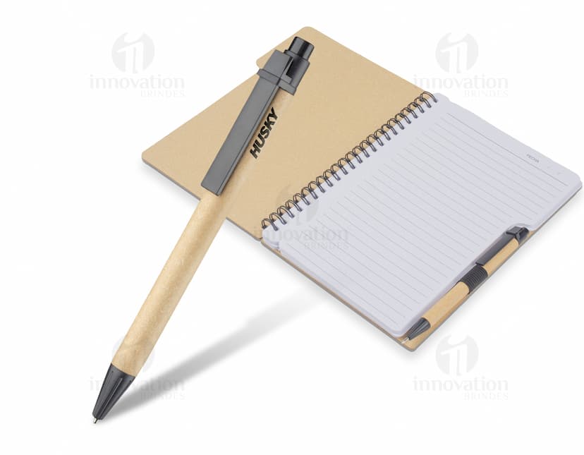 Caderno em couro amarelo listrado, aberto sobre uma mesa de madeira. Há páginas em branco com linhas pretas, um compasso e um lápis ao lado. A imagem transmite a ideia de organização, estudo e planejamento.