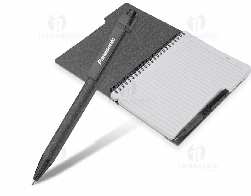 Caderno em branco aberto sobre a mesa de escritório, com uma caneta ao lado. O caderno tem capa de couro preta, folhas em espiral e espaço para escrever notas ou informações. A imagem mostra um local de trabalho limpo e organizado, ideal para fazer anotações, planejamentos ou estudos.