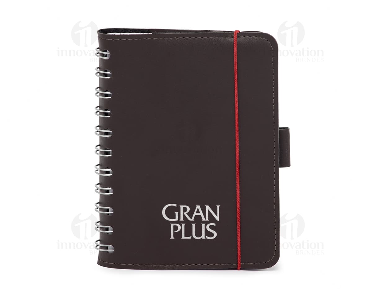 Caderneta de couro sintético preta aberta em cima de um notebook com páginas em branco e papel, escrita e organização de negócios e finanças, detalhes em couro, espaço para escrever e armazenar informações, design moderno e elegante.