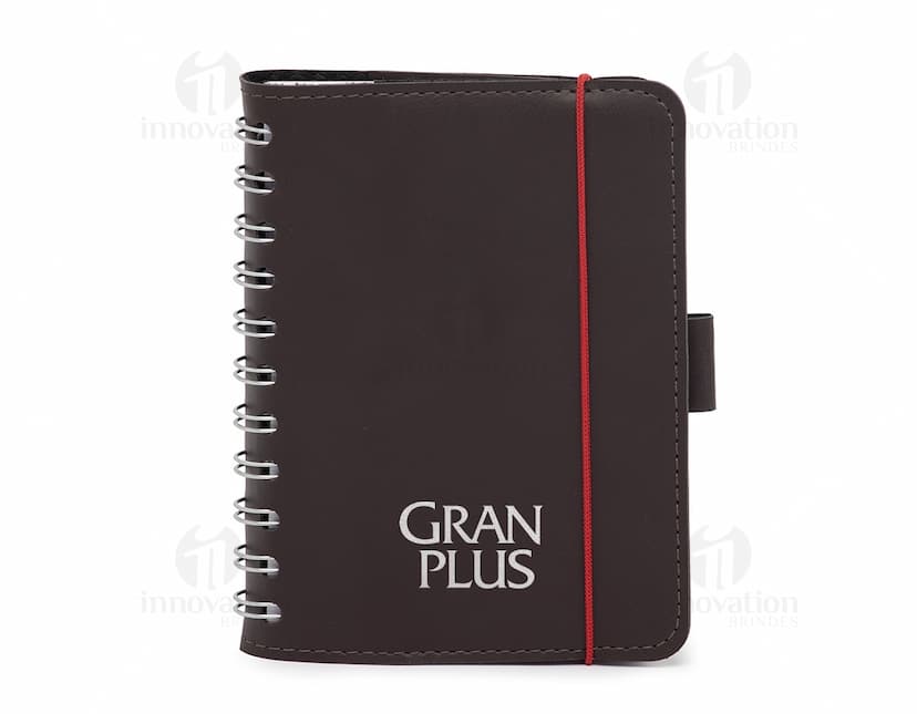 Caderneta de couro sintético preta aberta em cima de um notebook com páginas em branco e papel, escrita e organização de negócios e finanças, detalhes em couro, espaço para escrever e armazenar informações, design moderno e elegante.