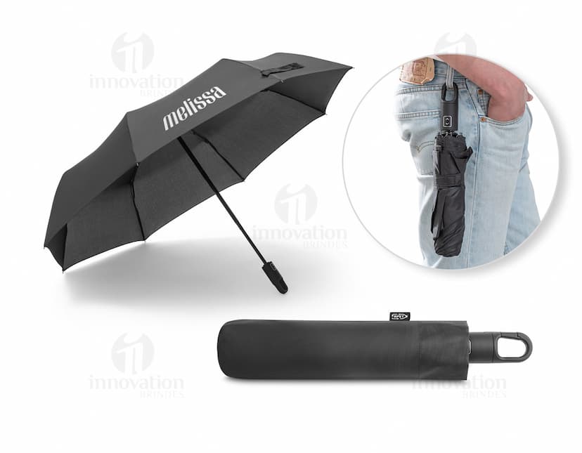 Guarda-chuva dobrável preto em formato de capelo de formatura, simbolizando sucesso e educação. O objeto 3D está aberto e vazio, sendo segurado por uma mão masculina. A imagem representa conhecimento, celebração e conquista acadêmica.