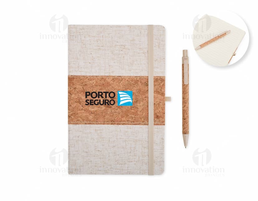Caixa de papelão marrom antiga e vazia com tampa aberta, contendo um livro de capa dura de cor preta e uma caderneta de papel amarelo, empilhados sobre uma mesa de madeira vintage.