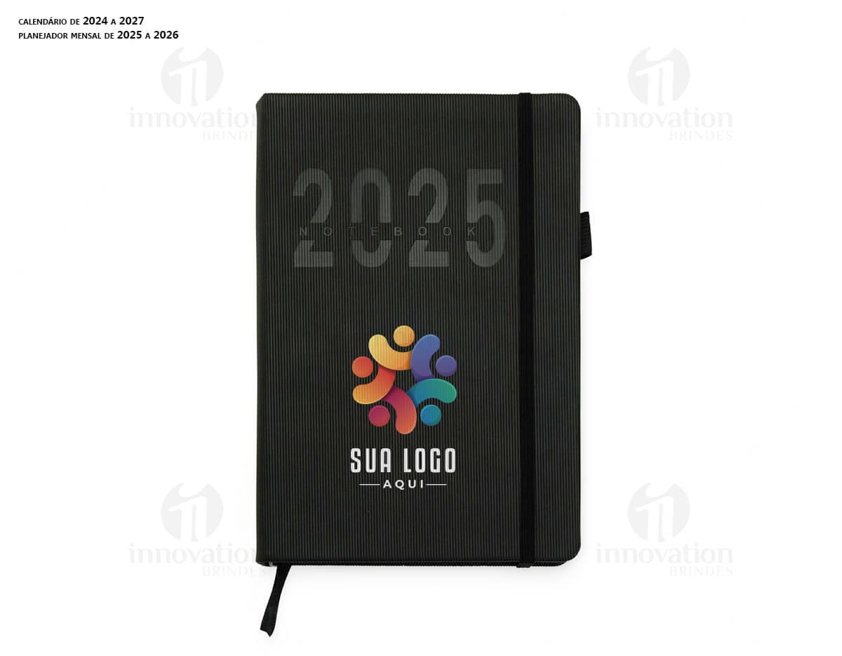 Agenda Diária 2025 em couro marrom, aberta sobre um notebook preto com papel em branco, teclado de computador e diversos objetos de escritório ao redor, como caneta, carteira, pasta e dinheiro.