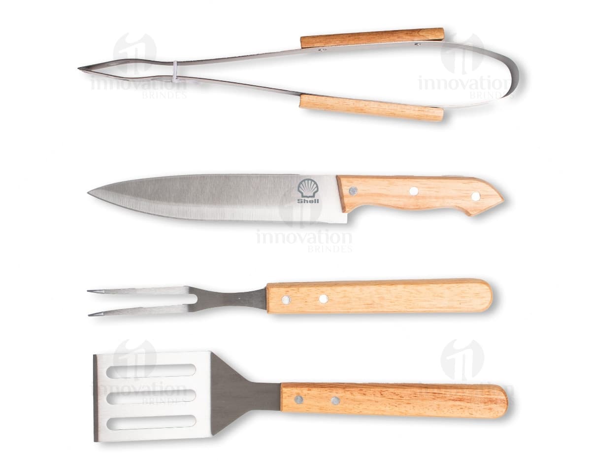 Kit churrasco 4 peças em aço inoxidável, composto por faca, garfo, pinça e pegador, isolados em fundo branco.