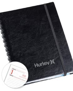 Agenda executiva em couro preto com fecho metálico e folhas de papel em branco.