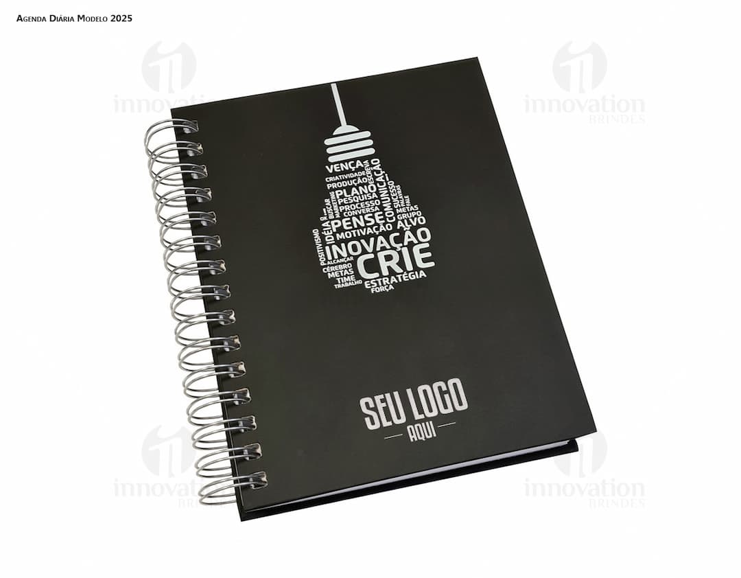 Agenda Wire-o em formato de espiral com capa preta e páginas em branco aberta em cima de uma mesa de escritório.