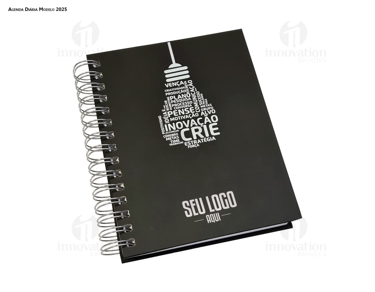 Agenda Wire-o em formato de espiral com capa preta e páginas em branco aberta em cima de uma mesa de escritório.