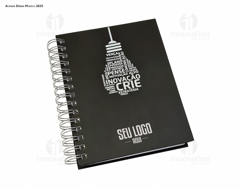 Agenda Wire-o em formato de espiral com capa preta e páginas em branco aberta em cima de uma mesa de escritório.