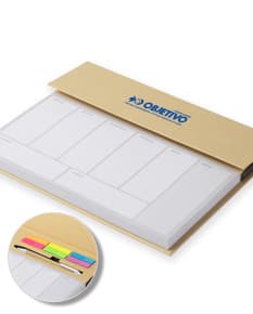 Bloco de anotações com planejamento aberto em uma mesa de escritório. No bloco, é possível ver páginas decoradas e datas planejadas. Além disso, há canetas e clips ao redor do bloco.
