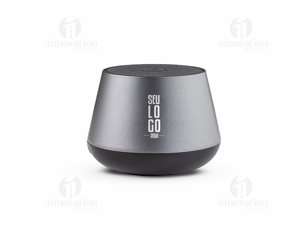 Caixinha de som wireless portátil com design compacto e elegante, na cor preta. Aparelho com botões de controle e luz indicadora de funcionamento. Ideal para ouvir música em qualquer lugar.