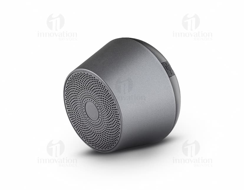 Caixinha de som wireless portátil com design compacto e elegante, na cor preta. Aparelho com botões de controle e luz indicadora de funcionamento. Ideal para ouvir música em qualquer lugar.