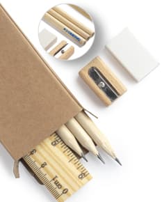 Kit escritório contendo caneta, caderno, borracha e clips de papel sobre a mesa de madeira.