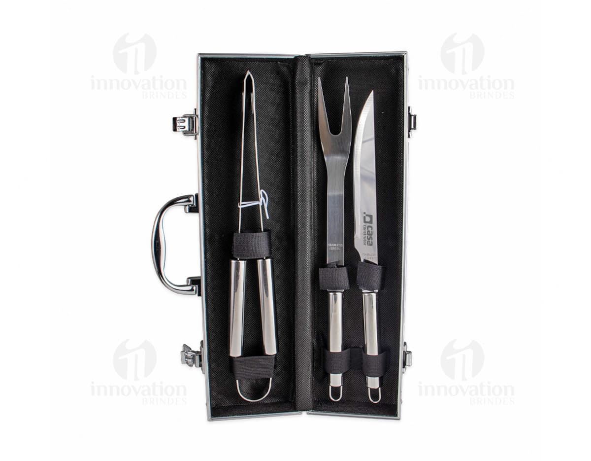 Kit Churrasco 3 Peças em aço inoxidável, contendo faca, garfo e pegador, sobre fundo branco.