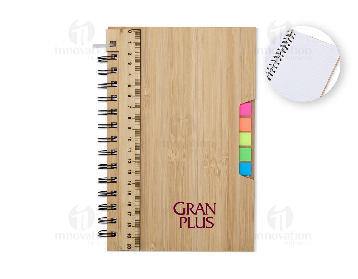 Caderno A5 Bambu em textura de bambu, aberto e com páginas em branco. Possui régua de medição, instrumento de medição, notebook, papel, anotações, espaço para escrever e design clean. Ideal para estudo, trabalho ou projetos.