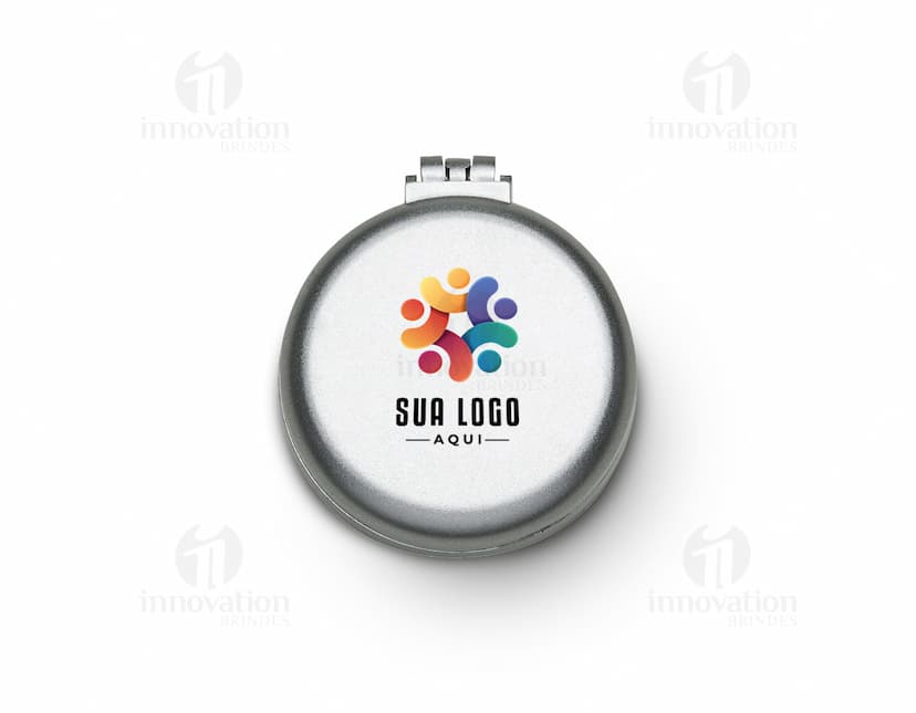 Espelho de bolsa com escova preta e vermelha, feito de vidro e metal, com um botão redondo para fechar. Possui um ícone de lupa prateada, símbolo de pesquisa e ampliação. O objeto é um instrumento de maquiagem compacto e prático para levar na bolsa, ideal para retoques durante o dia.