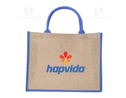 Saco de yute marrón con asas cortas y detalles en burdeos, sobre fondo blanco.