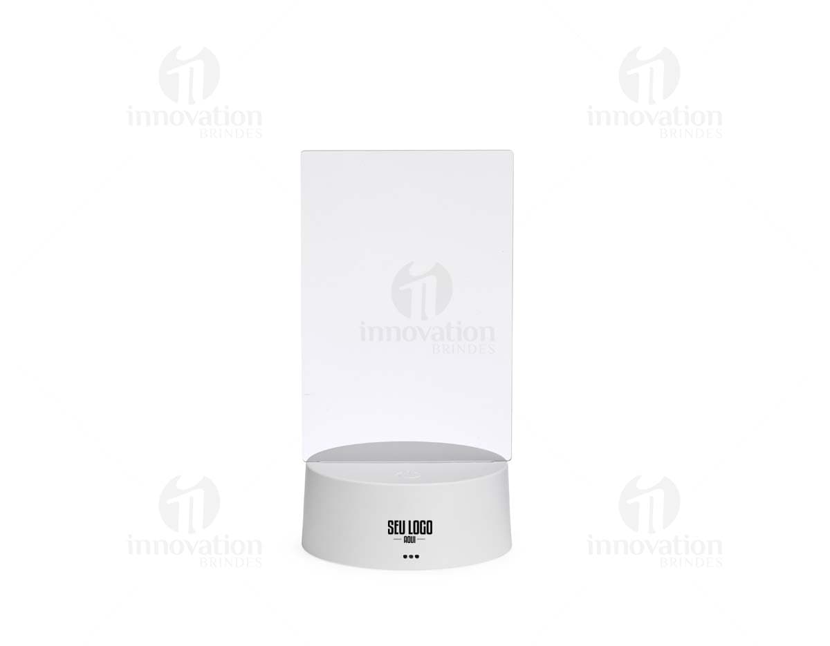 Luminária Led de Mesa na cor preta, com hastes flexíveis e base redonda. Acesa, iluminando um ambiente com luz branca.