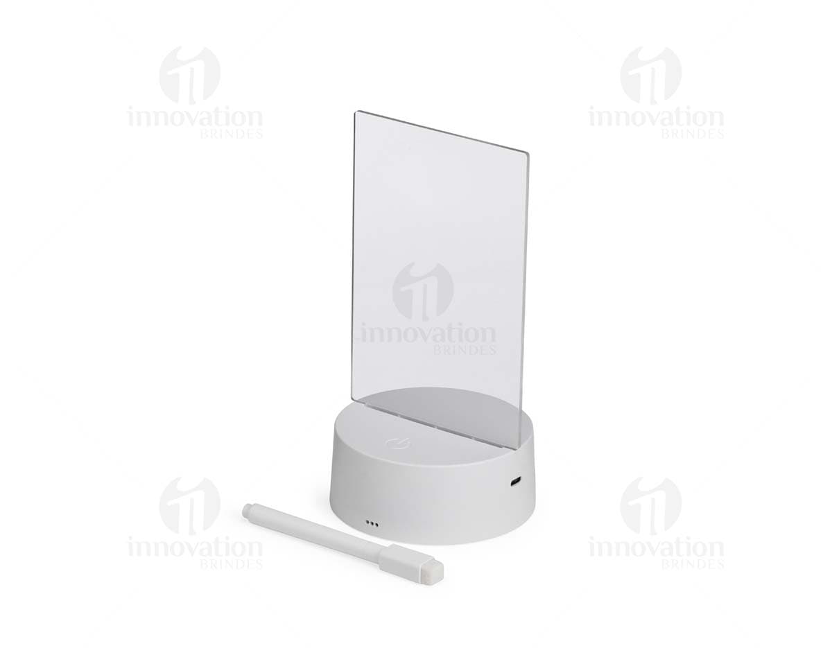 Luminária Led de Mesa na cor preta, com hastes flexíveis e base redonda. Acesa, iluminando um ambiente com luz branca.