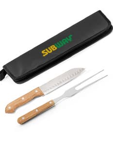 Kit churrasco com estojo contendo diversos utensílios em aço inoxidável, como faca, garfo, espeto, luva e pegador de carnes. Ideal para uso em churrascos e eventos ao ar livre.
