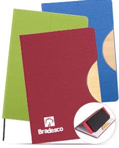 Caderneta com suporte de celular em uma mesa de escritório com notebook, papel em branco, cartão vazio, notas amarelas, livro, textos, padrões e texturas coloridas.