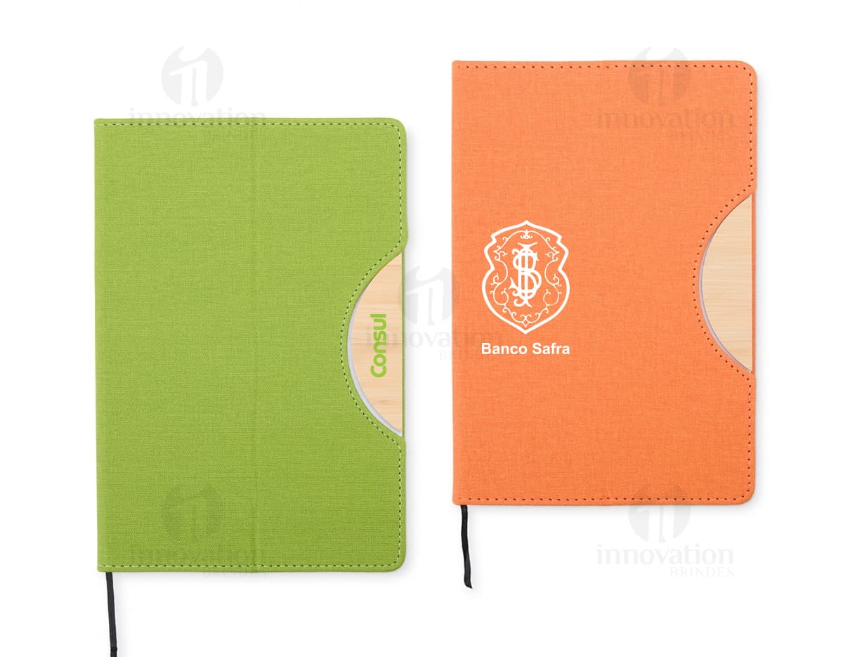 Caderneta com suporte de celular em uma mesa de escritório com notebook, papel em branco, cartão vazio, notas amarelas, livro, textos, padrões e texturas coloridas.