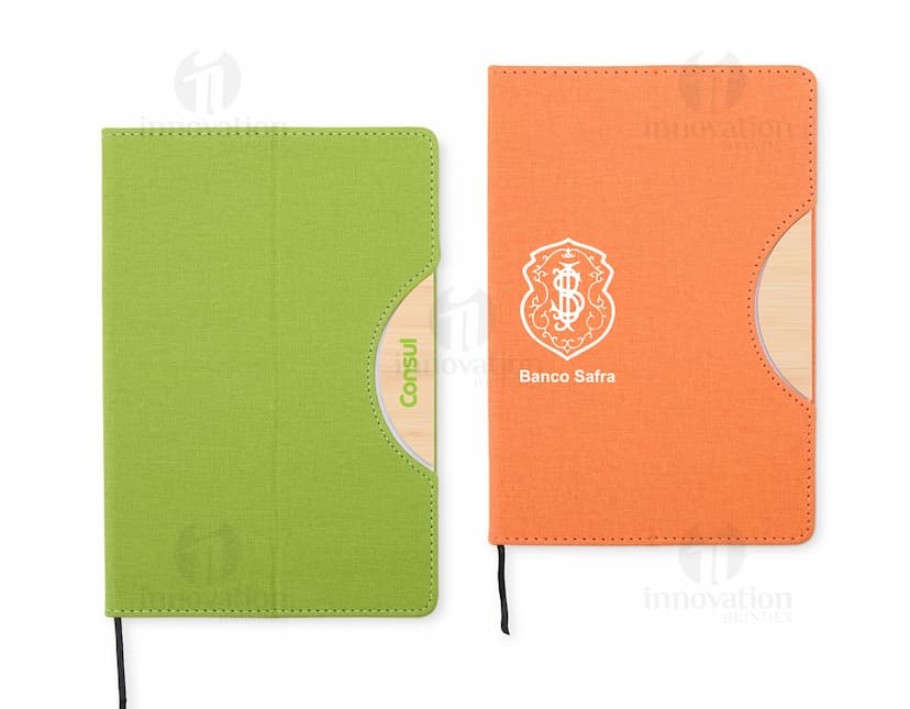 Caderneta com suporte de celular em uma mesa de escritório com notebook, papel em branco, cartão vazio, notas amarelas, livro, textos, padrões e texturas coloridas.