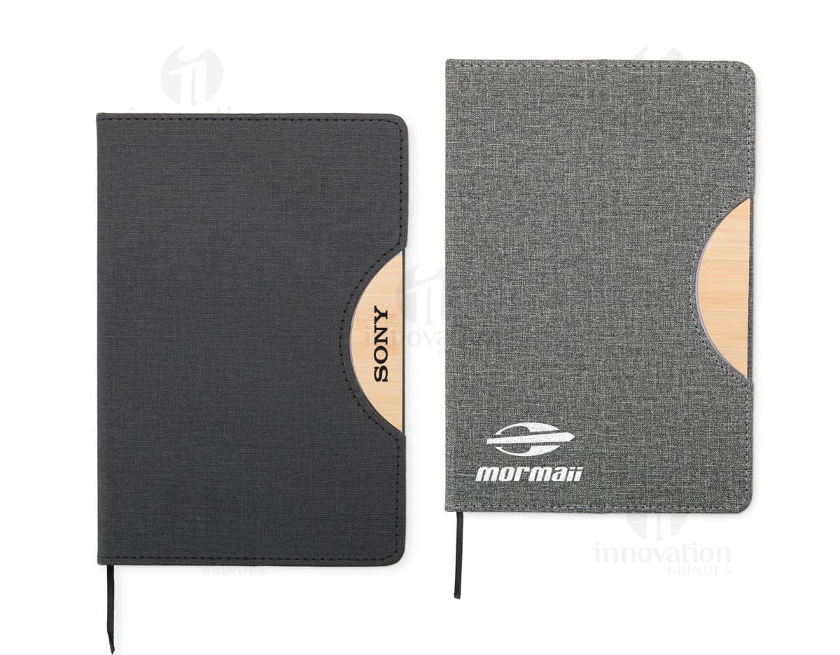 Caderneta com suporte de celular em uma mesa de escritório com notebook, papel em branco, cartão vazio, notas amarelas, livro, textos, padrões e texturas coloridas.