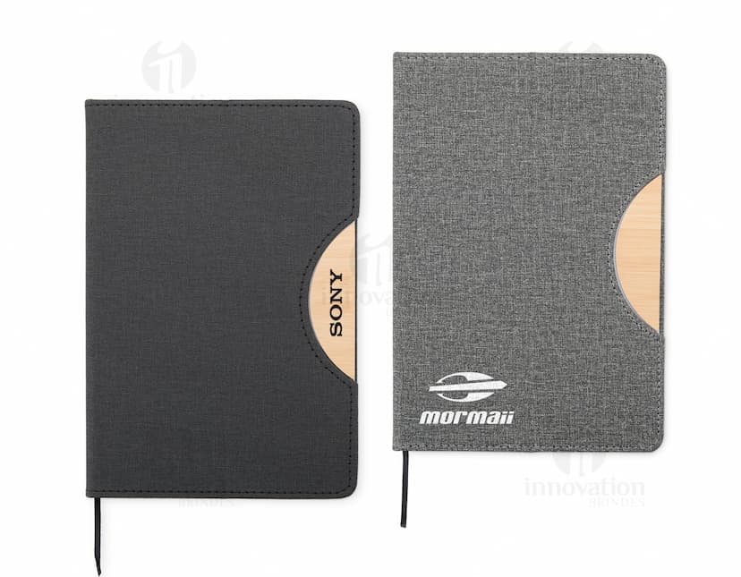 Caderneta com suporte de celular em uma mesa de escritório com notebook, papel em branco, cartão vazio, notas amarelas, livro, textos, padrões e texturas coloridas.