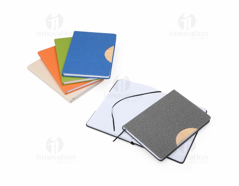 Caderneta com suporte de celular em uma mesa de escritório com notebook, papel em branco, cartão vazio, notas amarelas, livro, textos, padrões e texturas coloridas.
