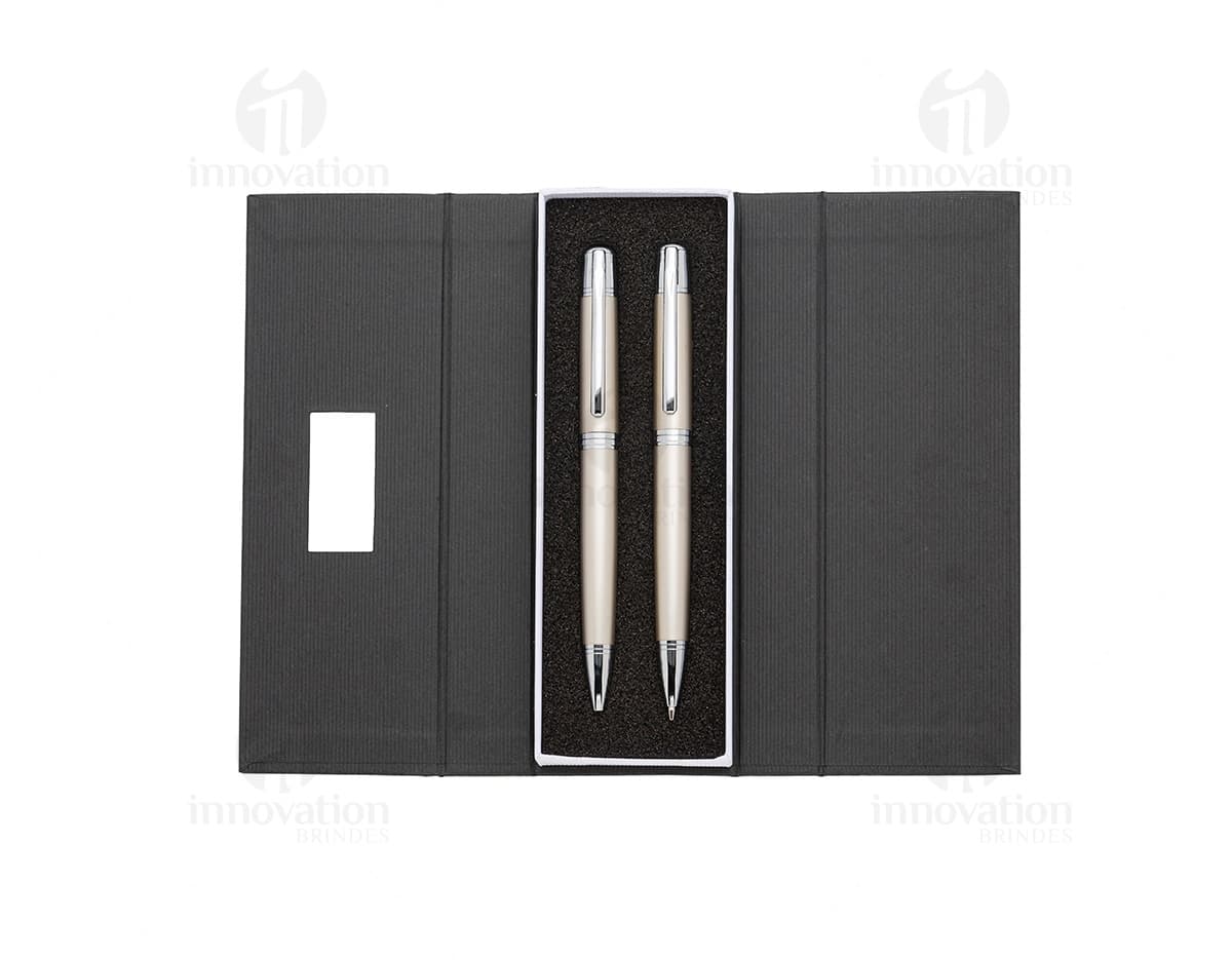 Conjunto de caneta e lapiseira de metal em fundo branco. A caneta e a lapiseira possuem detalhes cromados e são apresentadas em uma caixa elegante.