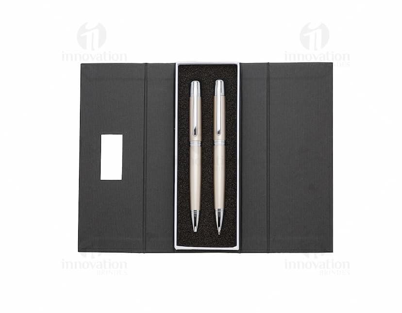 Conjunto de caneta e lapiseira de metal em fundo branco. A caneta e a lapiseira possuem detalhes cromados e são apresentadas em uma caixa elegante.
