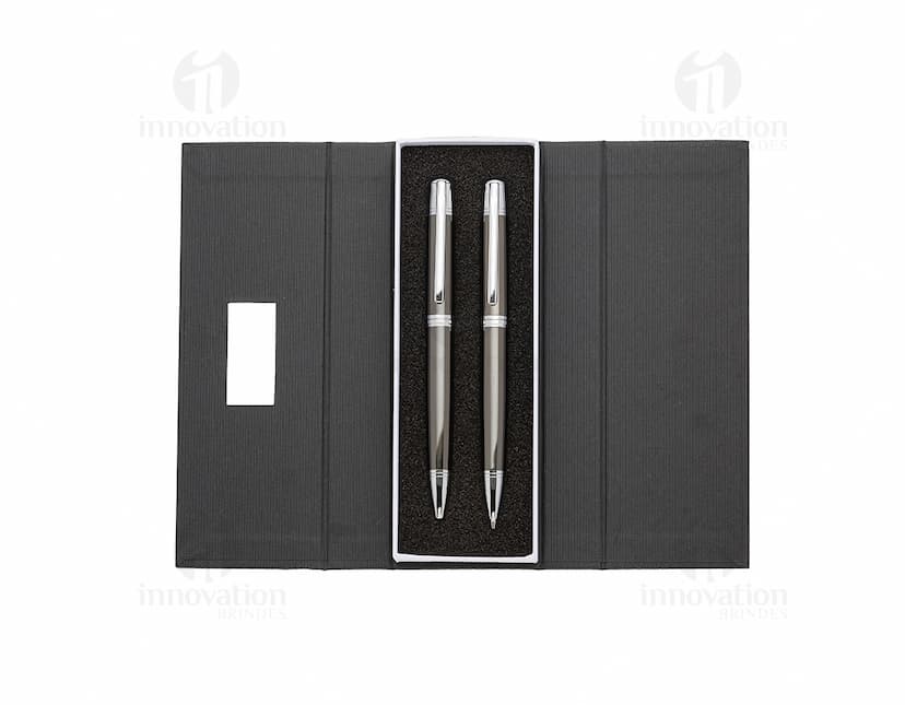 Conjunto de caneta e lapiseira de metal em fundo branco. A caneta e a lapiseira possuem detalhes cromados e são apresentadas em uma caixa elegante.