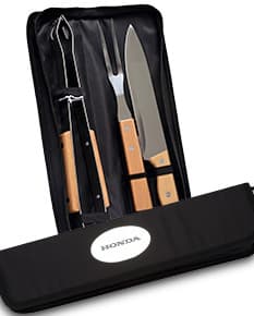 Kit churrasco composto por 3 peças: faca, garfo e pegador de carne em aço inoxidável, sobre fundo de madeira.