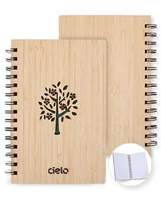 Caderno Bambu com capa de tecido estampado em tons de verde e marrom, folhas em papel reciclado e marcador de páginas de fita verde.