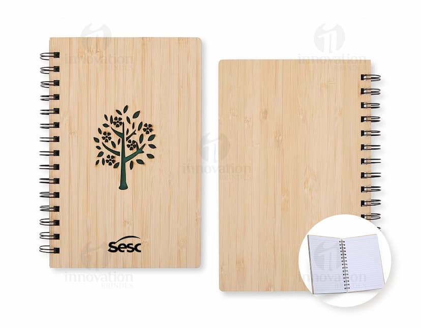 Caderno Bambu com capa de tecido estampado em tons de verde e marrom, folhas em papel reciclado e marcador de páginas de fita verde.