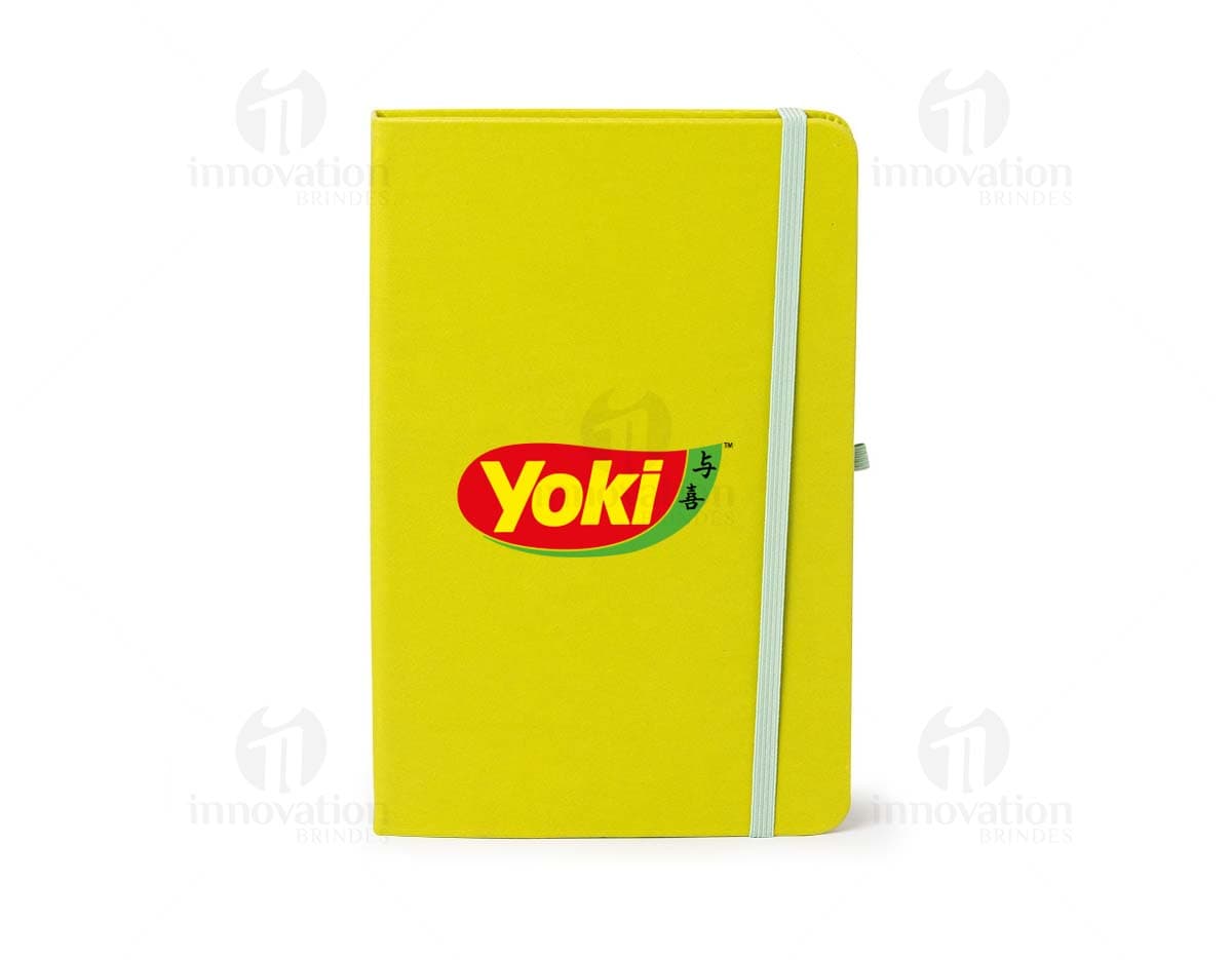 Caderneta de couro sintético vazia em um escritório amarelo, com espaço para inserir notas e documentos.