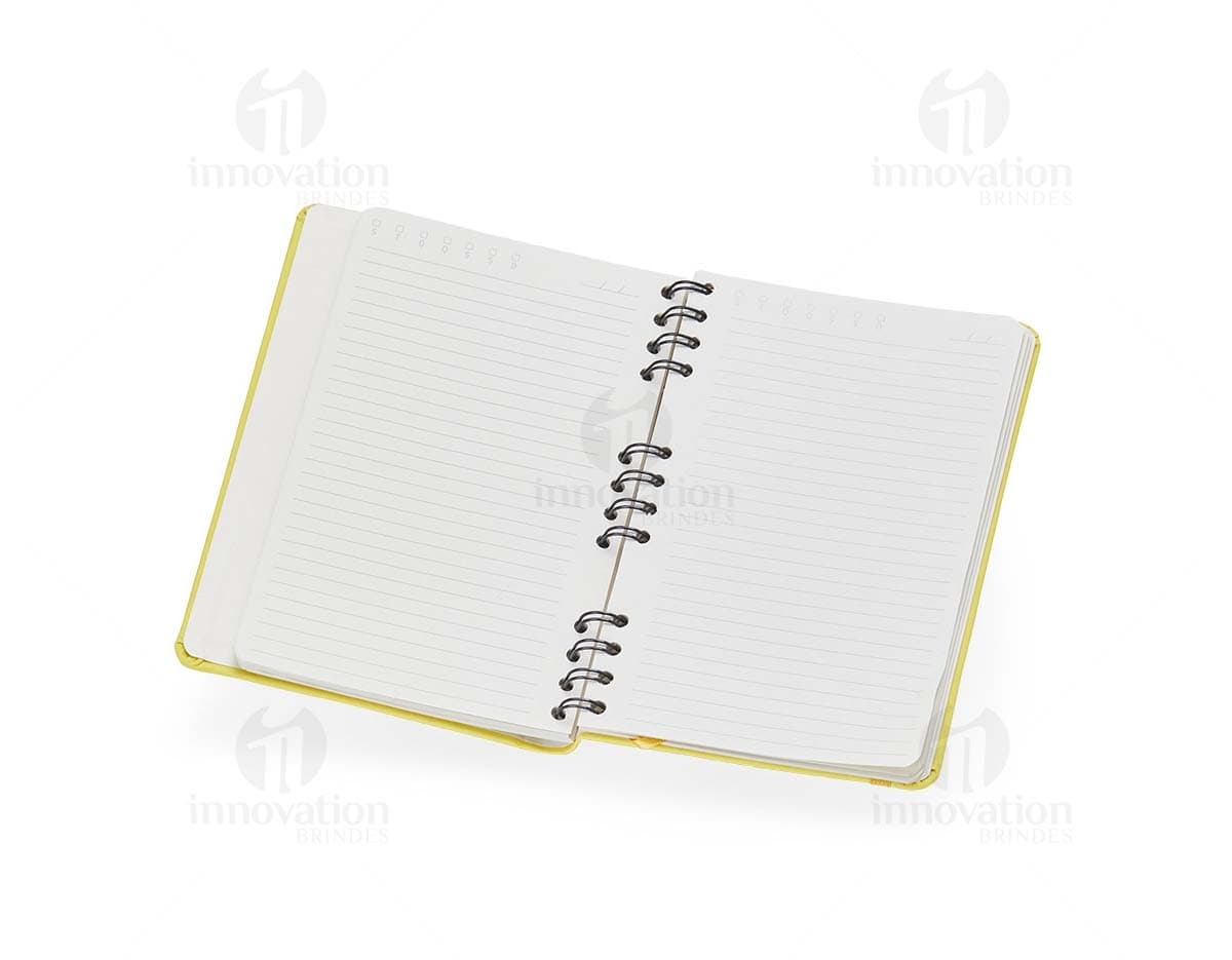 Caderneta Emborrachada com Wire-o em amarelo, design de quadro adesivo vazio em um notebook aberto, com papel em branco e um envelope de papel à direita, sobre fundo liso e limpo.