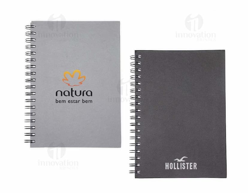 Caderno Cromato em design preto, com páginas em branco para anotações e espaço para adicionar mensagens e listas. Possui capa de proteção marrom em textura de madeira e anéis para manter as páginas organizadas. Ideal para uso no escritório, estudo ou reuniões de negócios.