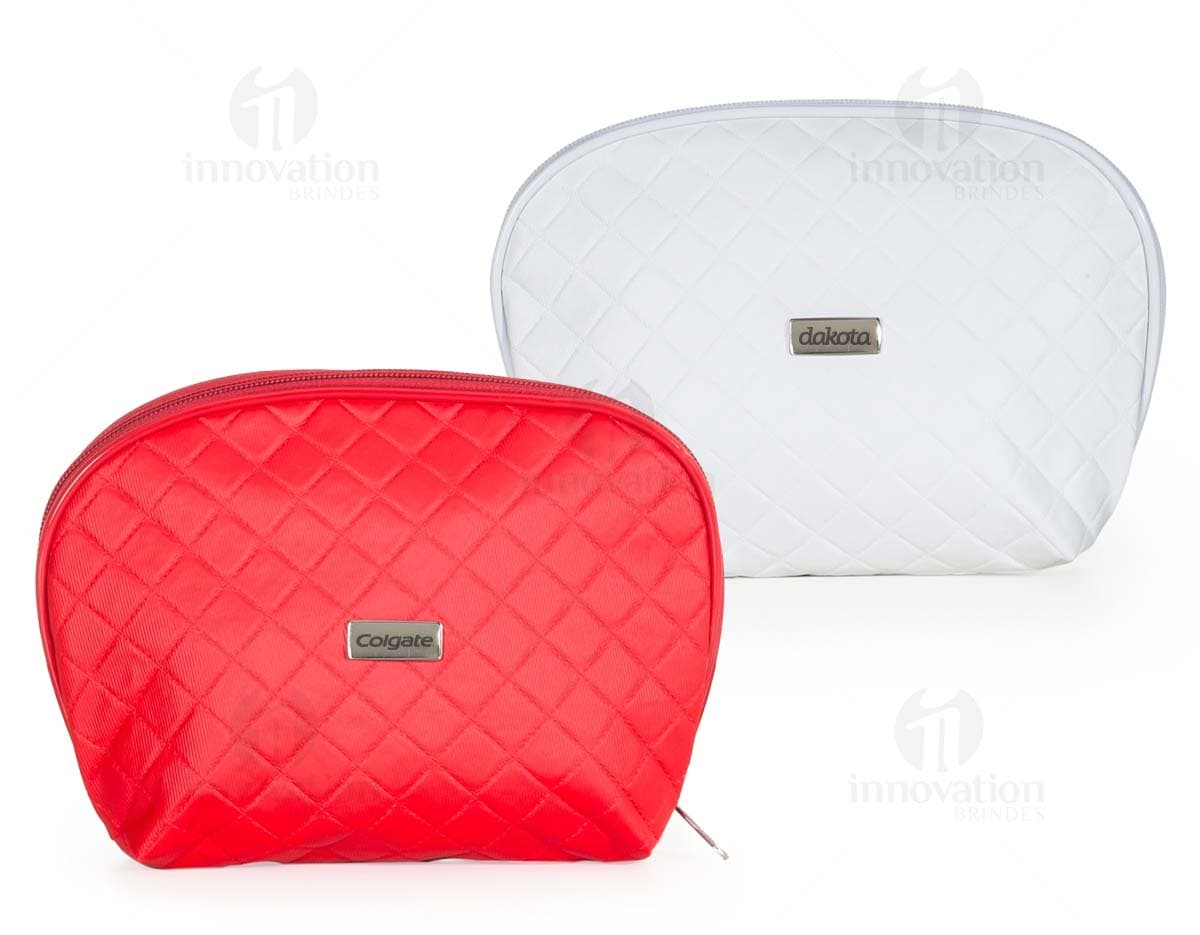 Necessaire de couro marrom com matelassê, estilo vintage, com fecho de fivela e alça de metal. O objeto está aberto, mostrando o interior vazio e forrado de papel. O design é elegante e fashion, com detalhes em couro e metal brilhante.