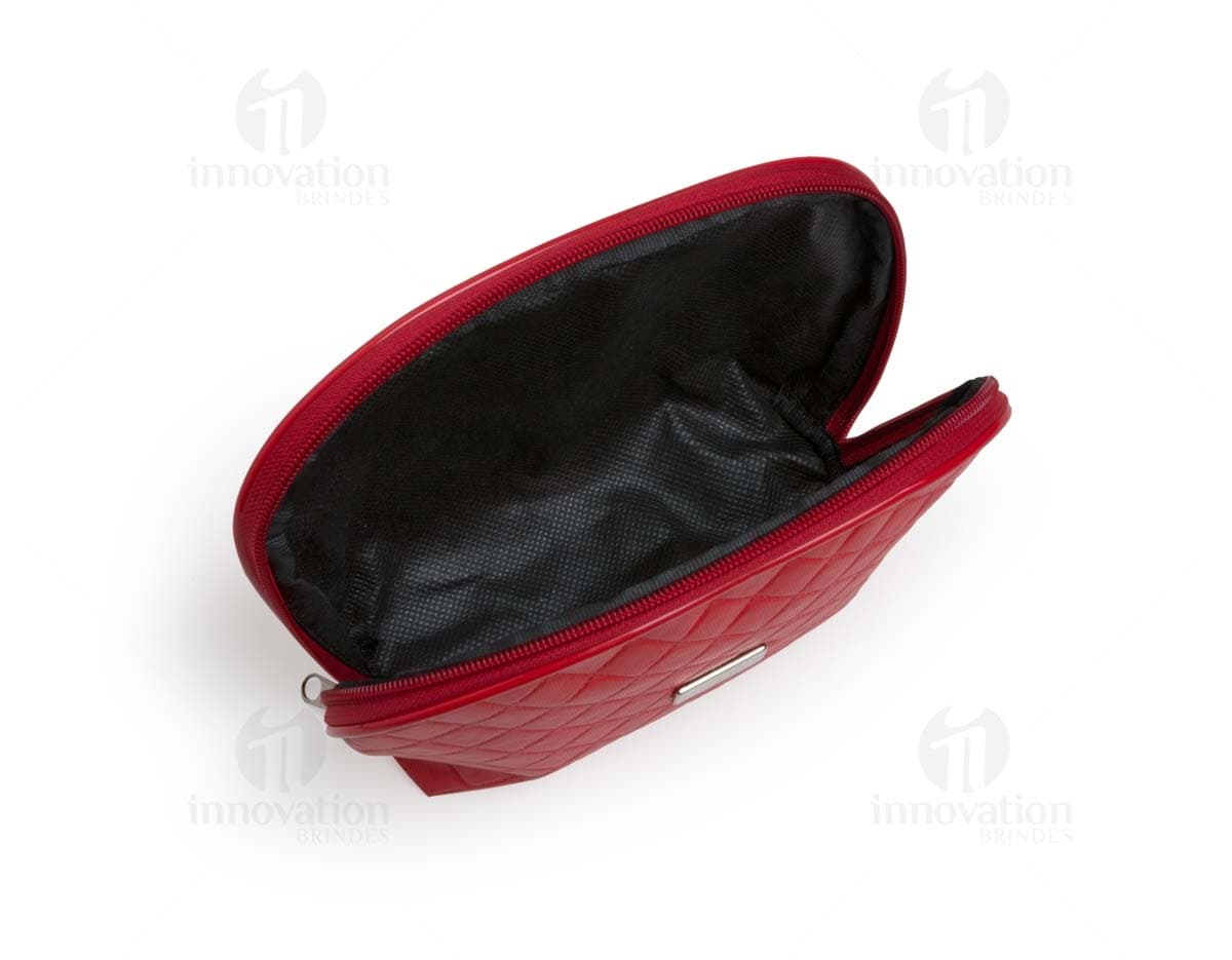 Necessaire de couro marrom com matelassê, estilo vintage, com fecho de fivela e alça de metal. O objeto está aberto, mostrando o interior vazio e forrado de papel. O design é elegante e fashion, com detalhes em couro e metal brilhante.