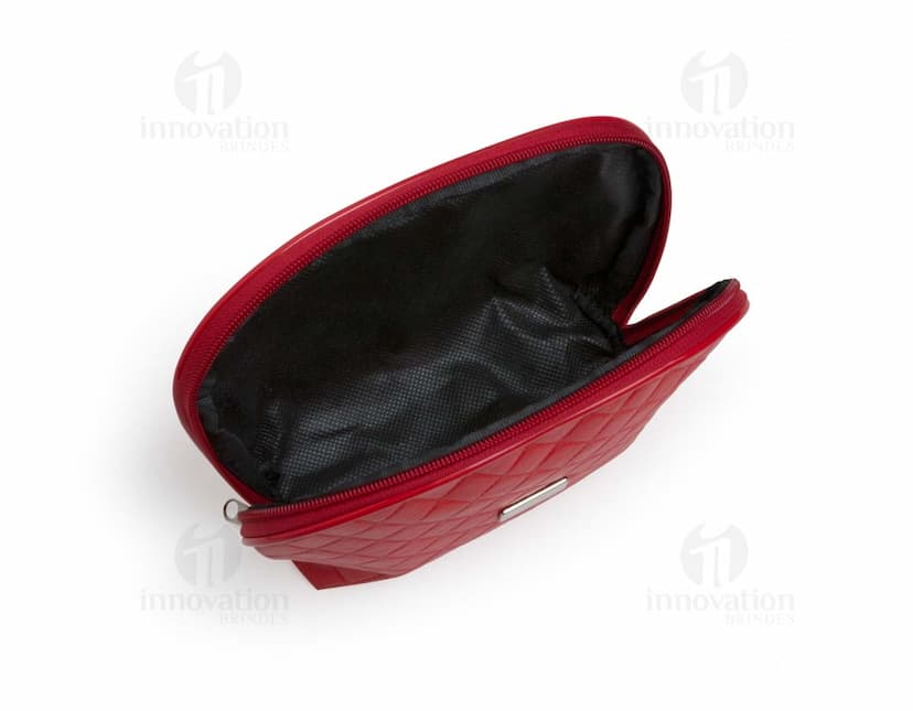 Necessaire de couro marrom com matelassê, estilo vintage, com fecho de fivela e alça de metal. O objeto está aberto, mostrando o interior vazio e forrado de papel. O design é elegante e fashion, com detalhes em couro e metal brilhante.