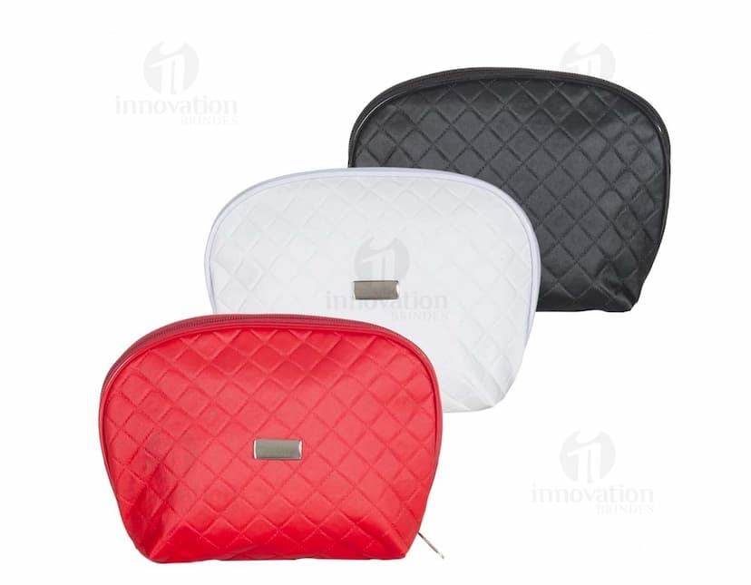 Necessaire de couro marrom com matelassê, estilo vintage, com fecho de fivela e alça de metal. O objeto está aberto, mostrando o interior vazio e forrado de papel. O design é elegante e fashion, com detalhes em couro e metal brilhante.