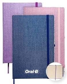 Caderneta A5 em papel texturizado antigo, com capa de tecido vintage em tom de marrom desgastado. O design é grunge e possui um padrão decorativo. O material é de fibra de algodão áspera, com uma superfície em canvas. Na capa, há um detalhe de costura em linha preta. O interior está em branco, com páginas vazias.