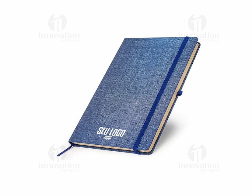 Caderneta A5 em papel texturizado antigo, com capa de tecido vintage em tom de marrom desgastado. O design é grunge e possui um padrão decorativo. O material é de fibra de algodão áspera, com uma superfície em canvas. Na capa, há um detalhe de costura em linha preta. O interior está em branco, com páginas vazias.