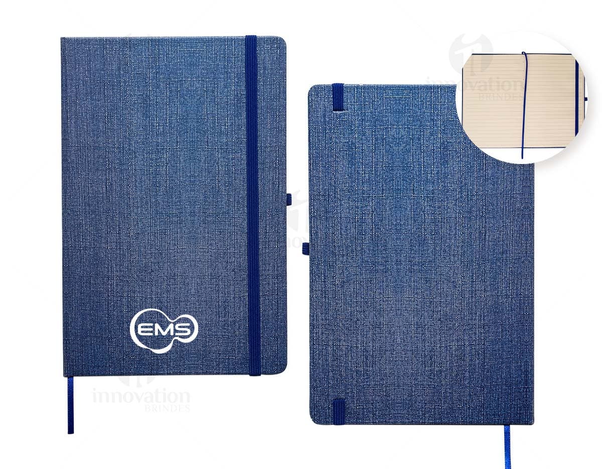 Caderneta A5 em papel texturizado antigo, com capa de tecido vintage em tom de marrom desgastado. O design é grunge e possui um padrão decorativo. O material é de fibra de algodão áspera, com uma superfície em canvas. Na capa, há um detalhe de costura em linha preta. O interior está em branco, com páginas vazias.