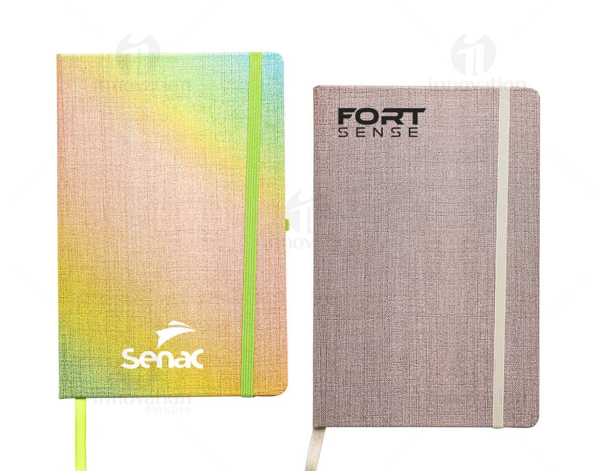 Caderneta A5 em papel texturizado antigo, com capa de tecido vintage em tom de marrom desgastado. O design é grunge e possui um padrão decorativo. O material é de fibra de algodão áspera, com uma superfície em canvas. Na capa, há um detalhe de costura em linha preta. O interior está em branco, com páginas vazias.