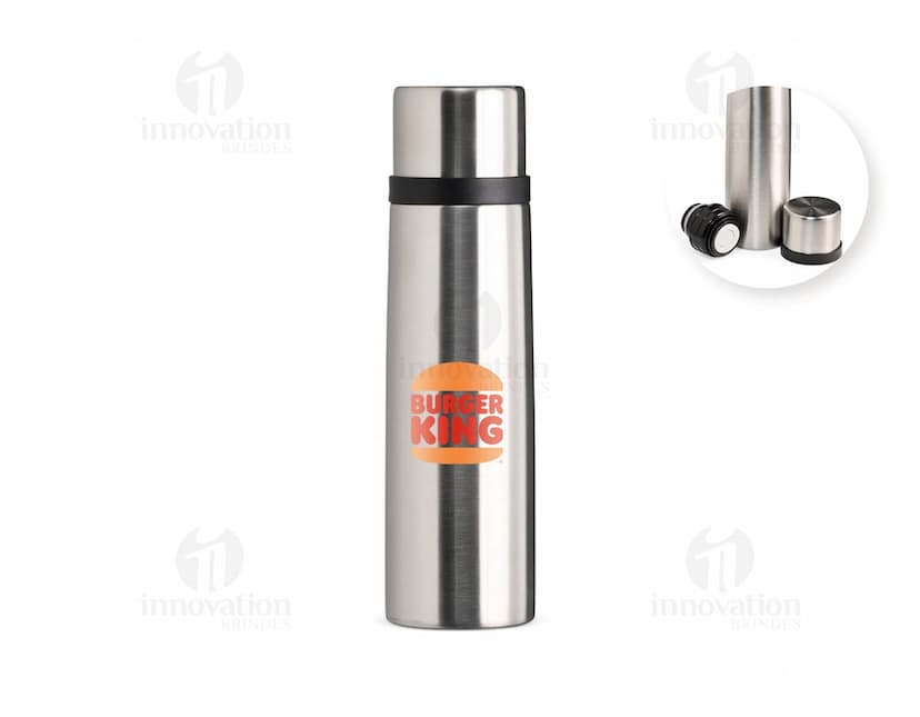 Garrafa térmica de 500ml em inox, com design elegante e tampa de metal, refletindo a luz. A garrafa é vazia e possui uma etiqueta amarela no corpo, garantindo frescor e praticidade para manter bebidas quentes ou frias. Ideal para uso em casa, no trabalho ou em viagens, proporcionando elegância e funcionalidade.
