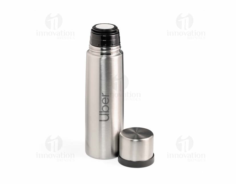 Garrafa térmica de 500ml em inox, com design elegante e tampa de metal, refletindo a luz. A garrafa é vazia e possui uma etiqueta amarela no corpo, garantindo frescor e praticidade para manter bebidas quentes ou frias. Ideal para uso em casa, no trabalho ou em viagens, proporcionando elegância e funcionalidade.